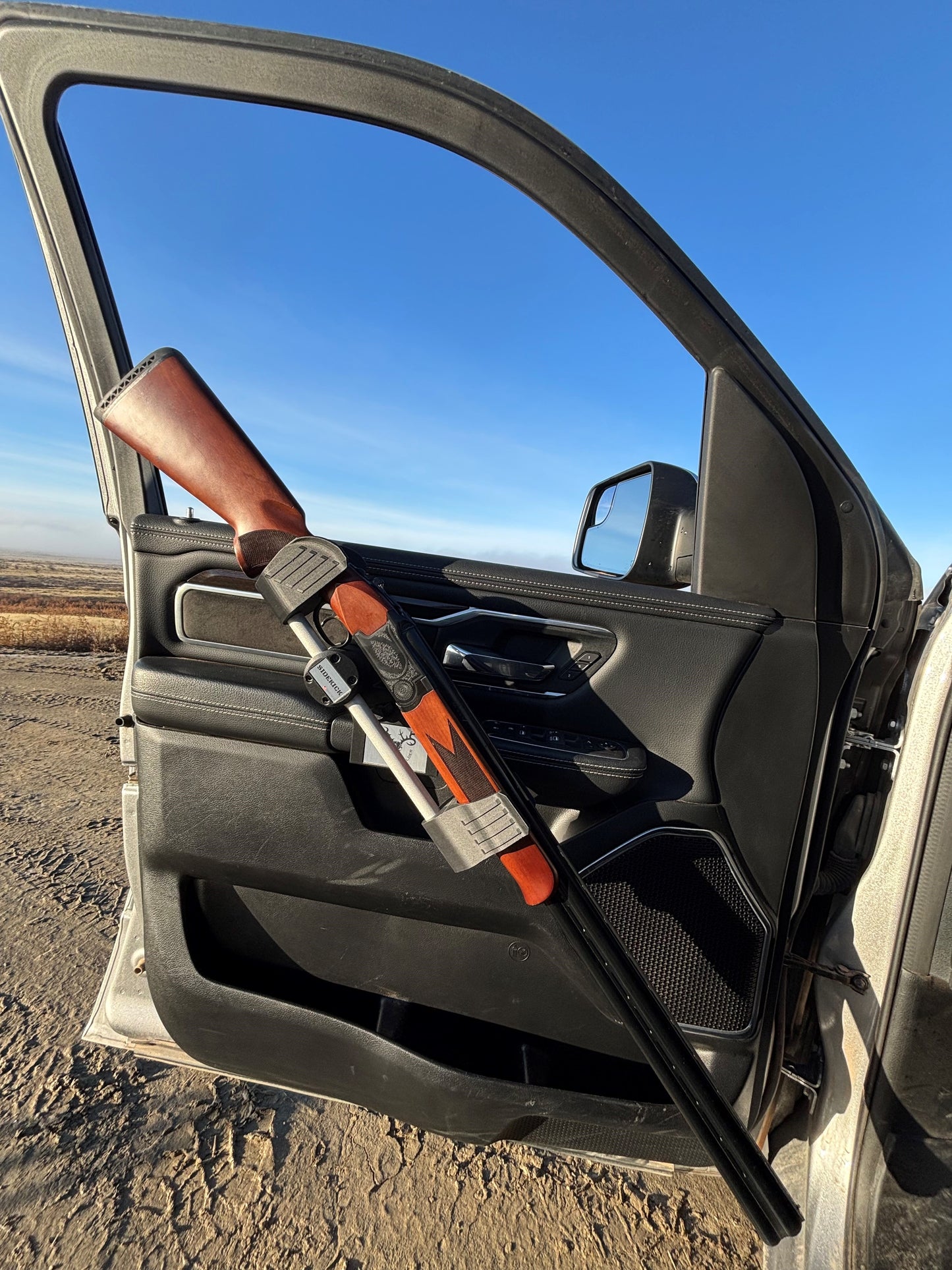 An Over/under 12ga shotgun safely secured in the Sidekick door mounted vehicle gun rack in a 2022 Ram 1500